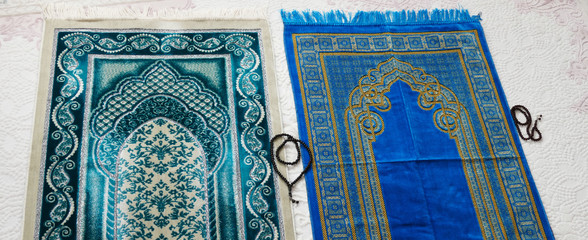 Islamic symbols, blue and green prayer rugs on a carpet in a house,