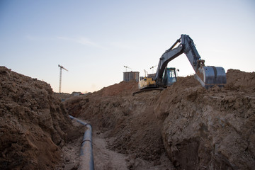 Excavator at work trenching at a construction site. Trench for laying external sewer pipes. Sewage...
