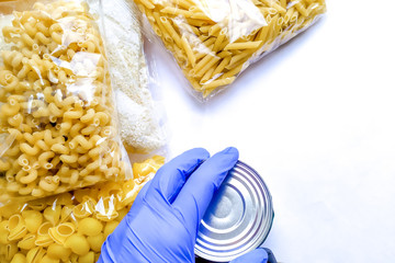 Food delivery to the coronavirus pandemic, a volunteer’s hand in a glove, donation delivery. Pasta, rice, canned food