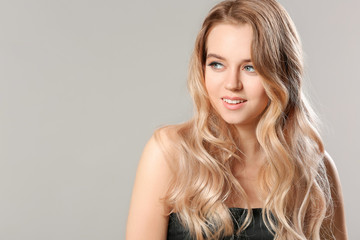 Young blonde with beautiful hair on grey background