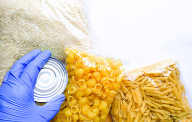 Food delivery to the coronavirus pandemic, a volunteer’s hand in a glove, donation delivery. Pasta, rice, canned food