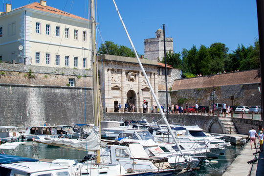 Zadar, Croatia; 07/17/2019: Lucica Fosa (Zadar harbour) full of boats with the Gate of Terraferma (or Gate of Zara) at the background