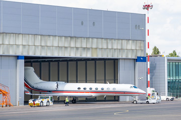 The pushback tug taxing the business jet from the hangar to the taxi strip