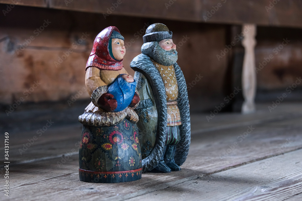 Wall mural folk craft of Russia, wooden painted doll in rural interiors, a man with a beard and a woman with a child in beautiful traditional clothes