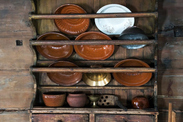 a cupboard for dishes in an old rural house, earthenware, large plates, cast iron, pot