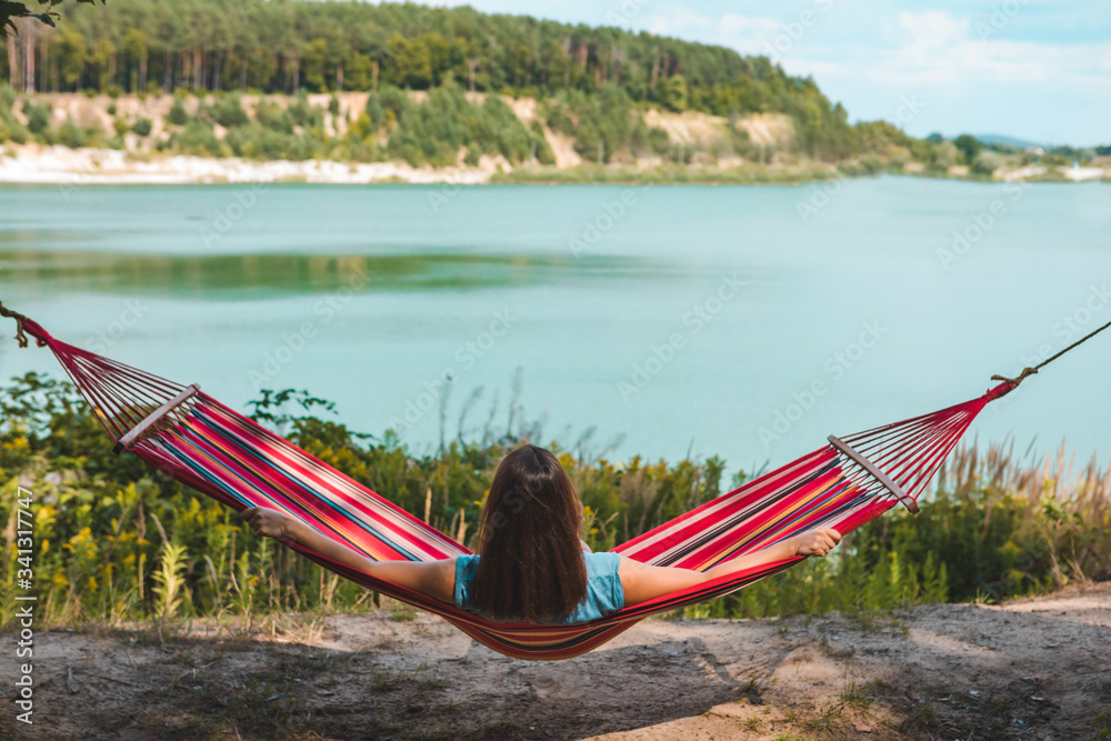 Poster woman laying on hammock enjoying the view of summer lake