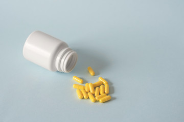 white jar with yellow capsules on a blue background