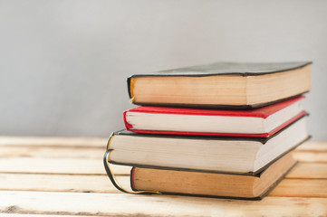 A stack of books on a wooden table.