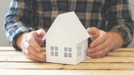 Paper house. Home security and protection purchase concept. Hand protection over the house.