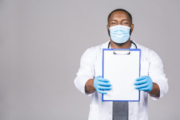 African american doctor man in face mask gloves isolated on grey background. Epidemic pandemic coronavirus 2019-ncov sars covid-19 flu virus. Holding clipboard.