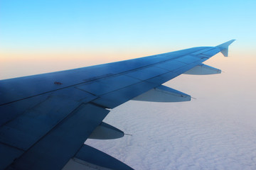 Fototapeta na wymiar Wing of the plane sunrise sky background