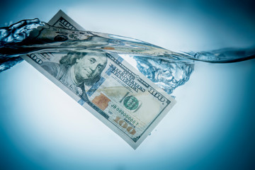 Global economic and financial crisis. US Dollar bills sinking in water as symbol of uncertain future of international trade and investment. Horizontal image.