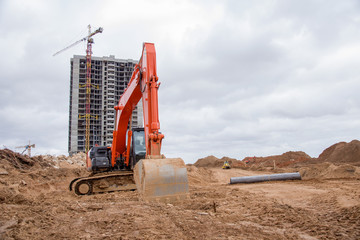 Red excavator during earthmoving at construction site. Backhoe dig ground for the construction of...