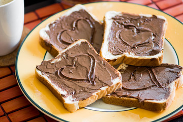 Slices of bread or toast with chocolate cream and mug of coffee and milk, heart shape
