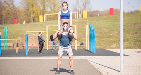 Athletic guy and girl doing leg exercises in medical masks during a pandemic. Squats COVID-19. Health care.