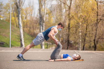 Athletic girl does leg press, kicks her man. Medical masked couple during a pandemic. COVID-19. Health care.