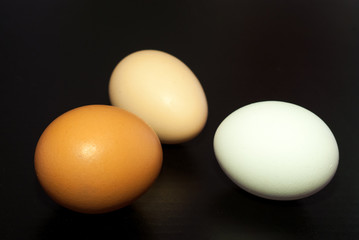three eggs of different colors on a black background close-up.  the idea of tolerance in society. racism concept isolated 