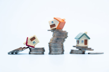 Mini house on stack of coins  on white background., Concept of Investment property, Investment risk and uncertainty in the real estate housing market.