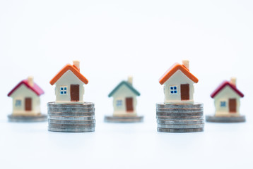 Mini house on stack of coins  on white background., Concept of Investment property, Investment risk and uncertainty in the real estate housing market.