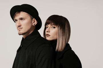 Portrait of urban fashion beautiful couple in black clothes posing over white background together. Close up fashion portrait of stylish young couple pretty woman and handsome man