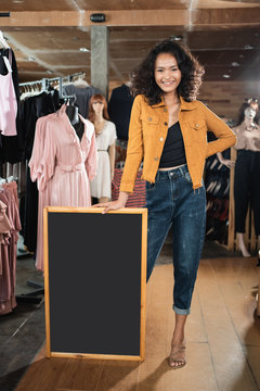 attractive young business owner holding chalkboard with 50 percent discout on the board