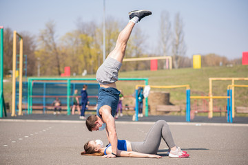A young sports guy in a medical mask stands in his arms over his girlfriend during a pandemic. COVID-19. Health care.