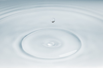 Small droplet of water falling over some ripple effect on the surface of water