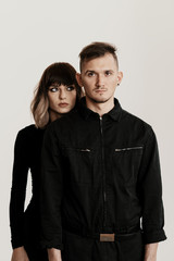 Portrait of urban fashion beautiful couple in black clothes posing over white background together. Close up fashion portrait of stylish young couple