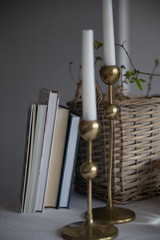 four books golden candlesticks wooden basket on a white tablecloth