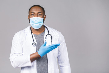 African american doctor man in medical gown sterile mask gloves isolated on grey background. Epidemic pandemic coronavirus 2019-ncov sars covid-19 flu virus. Pointing finger.