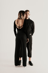 Portrait of urban fashion beautiful couple in black clothes posing over white background together. Close up fashion portrait of stylish young couple