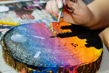 Obraz premium Girl uses colored paints brushes a picture in wooden