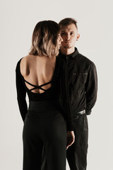 Portrait of urban fashion beautiful couple in black clothes posing over white background together. Close up fashion portrait of stylish young couple