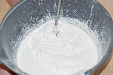 The white mixture for putty is mixed with a construction mixer.