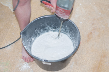 The builder stirs in a bucket a special mixture for repair