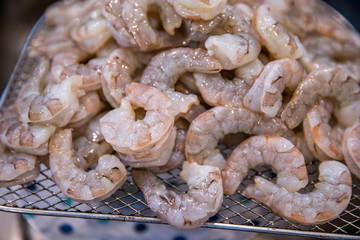 a tray filled with a pile of raw uncooked seafood, medium-sized peeled shrimp