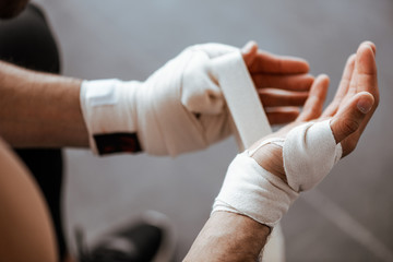 cropped view of man wrapping hand elastic sports bandage