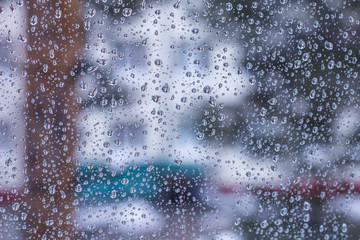 cityscape, blurred background behind wet glass with raindrops
