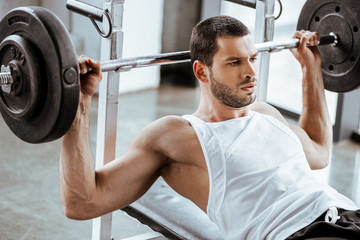 handsome sportsman working out with barbell in gym