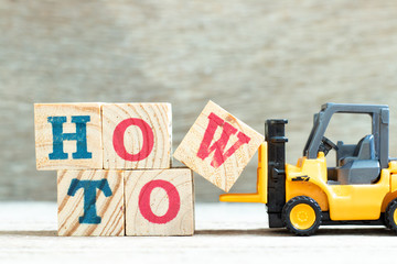 Toy forklift hold letter block w to complete word how to on wood background