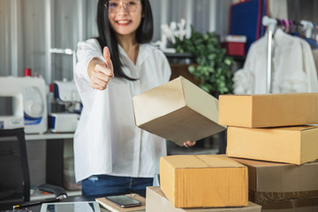 Young business woman working online e-commerce shopping at her shop. Young woman seller prepare...