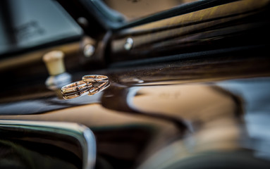 Wedding rings in old car interior. Car dashboard. Abstract ring shot.