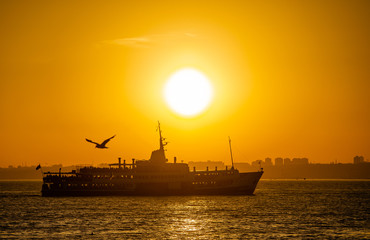 Ferry sails through the Bosphorus Strait in Istanbul, Turkey, during sunset