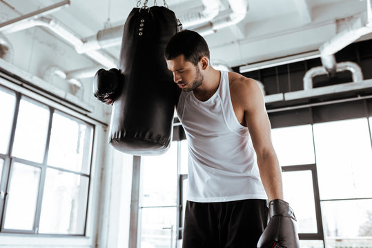 Tired Sportsman In Boxing Gloves Standing Near Punching Bag