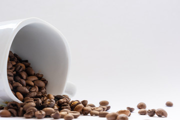coffee beans spill out of a ceramic cup