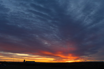 Obraz premium distant grain terminal silhouetted against sunset
