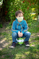 Child with face mask is playing with a ball