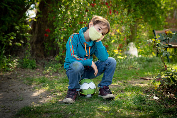 Child with face mask is playing with a ball