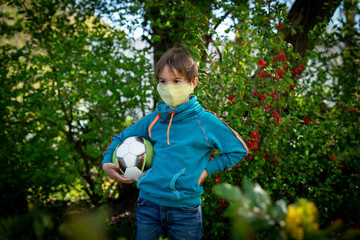 Child with face mask is playing with a ball