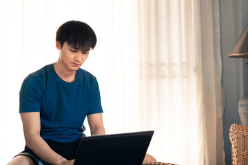 Handsome man playing laptop computer in the room, Work from home concept.